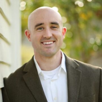 Brandon Renfro headshot wearing dark blazer and white button down shirt