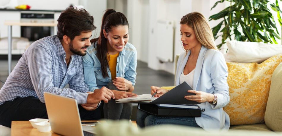 Couple sits with an insurance agent in their living as they go over options.