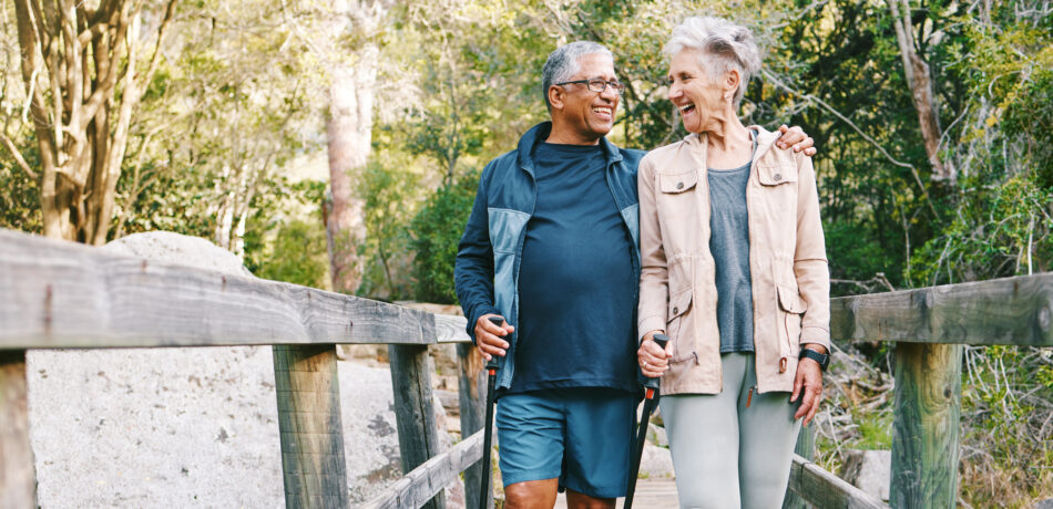 Couple smiles walking along a wooden footbridge while out on a nature hike.