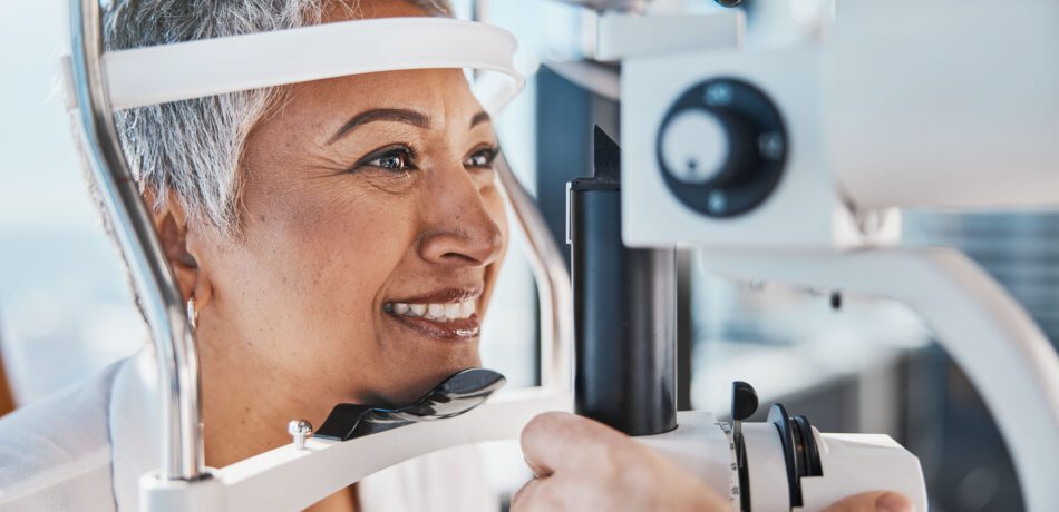 Older woman smiling while having an eye exam.