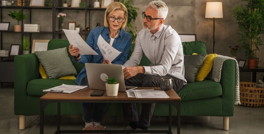 An older couple reviews papers in their living room.