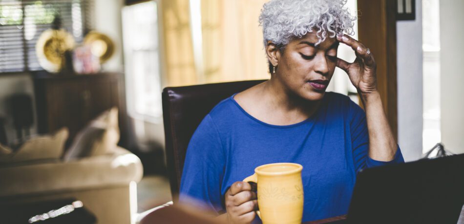 Stressed out woman working at laptop on table at home.