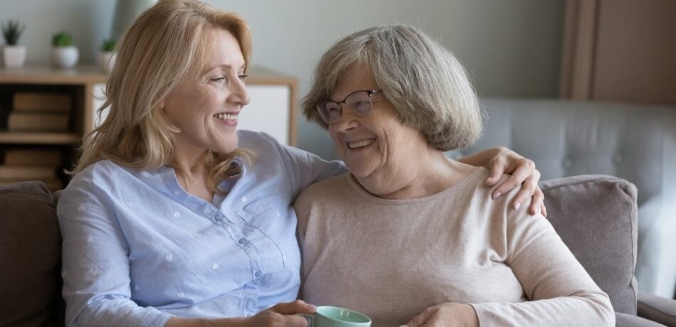 A mother and daughter embrace on a couch.