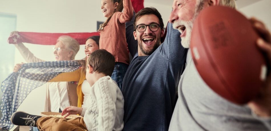 Cheerful extended family having fun while watching a victory of their favorite football team on TV at home.