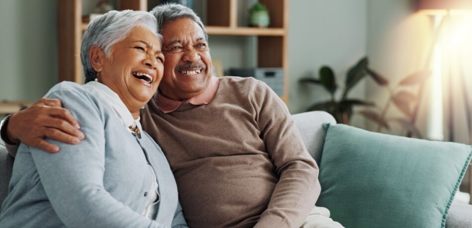Senior couple smiling on their couch.