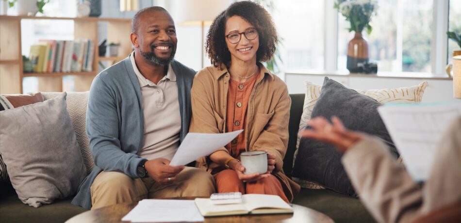 Couple listening to life insurance agent on couch.