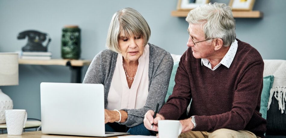 Shot of a senior couple going over their finances while sitting on their living room sofa at home.