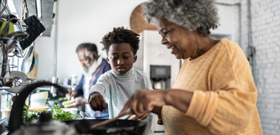 A grandmother cooks with her grandson.